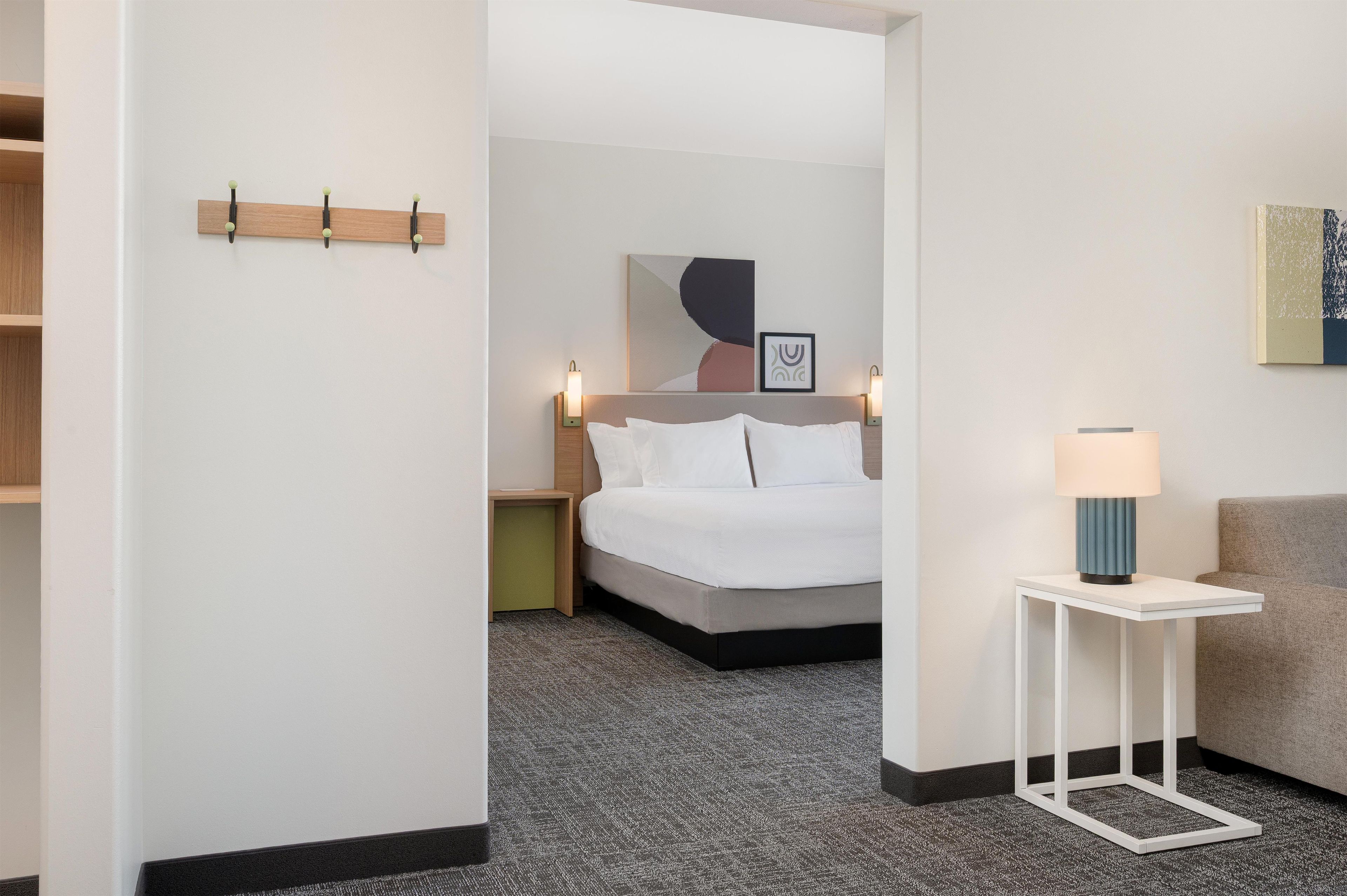 A hotel room with a bed, bedside tables, a lamp, and artwork on the walls.