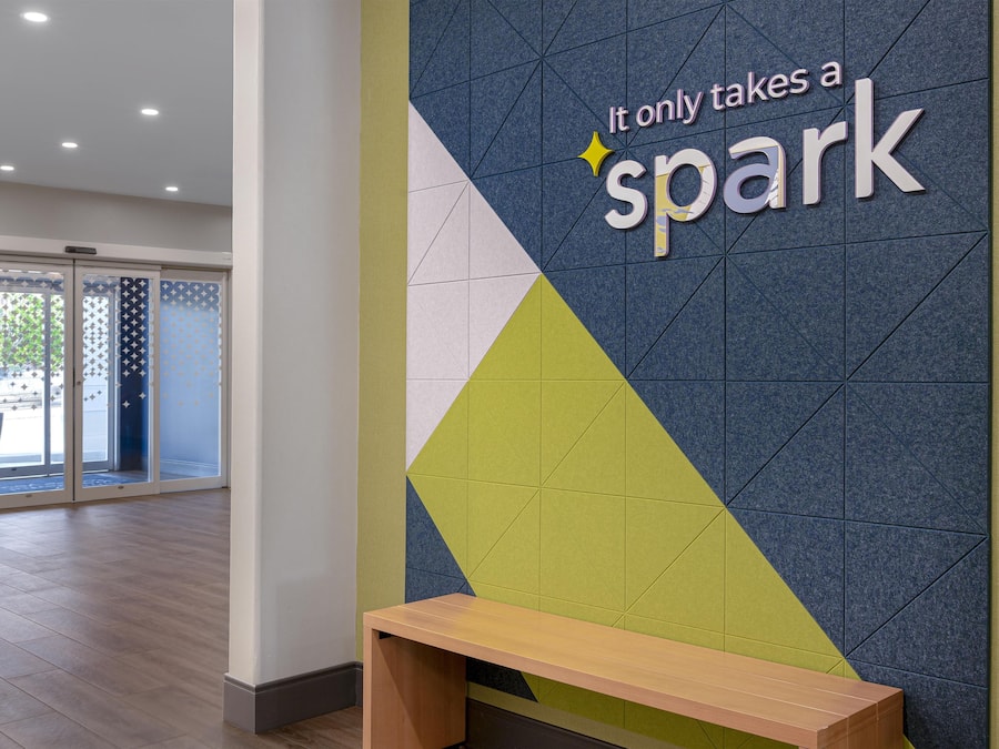 A reception area with a wall sign that reads 'It only takes a spark' and a wooden bench.