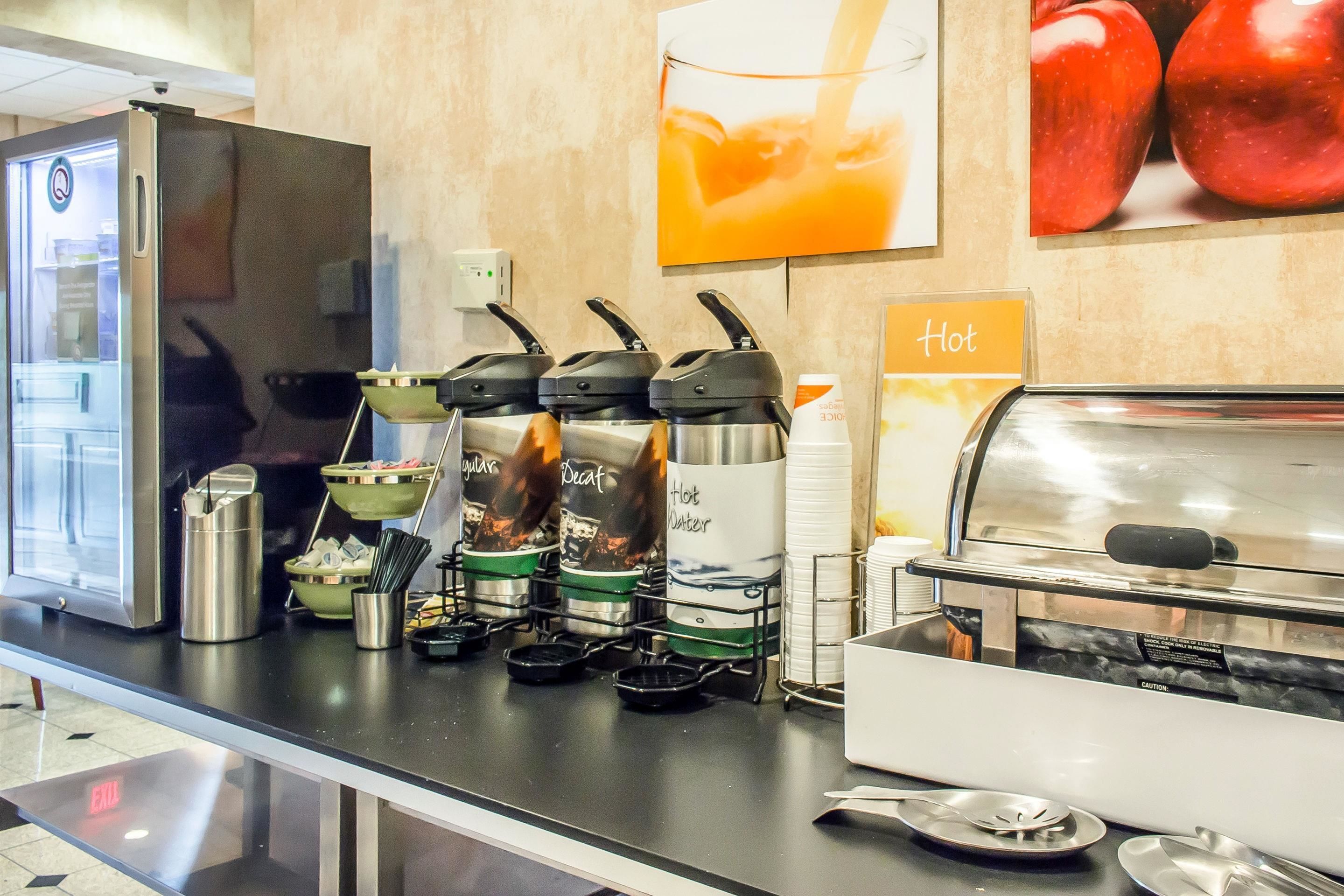 Una barra de desayuno con máquinas para hacer gofres, una cafetera y un dispensador de bebidas calientes.