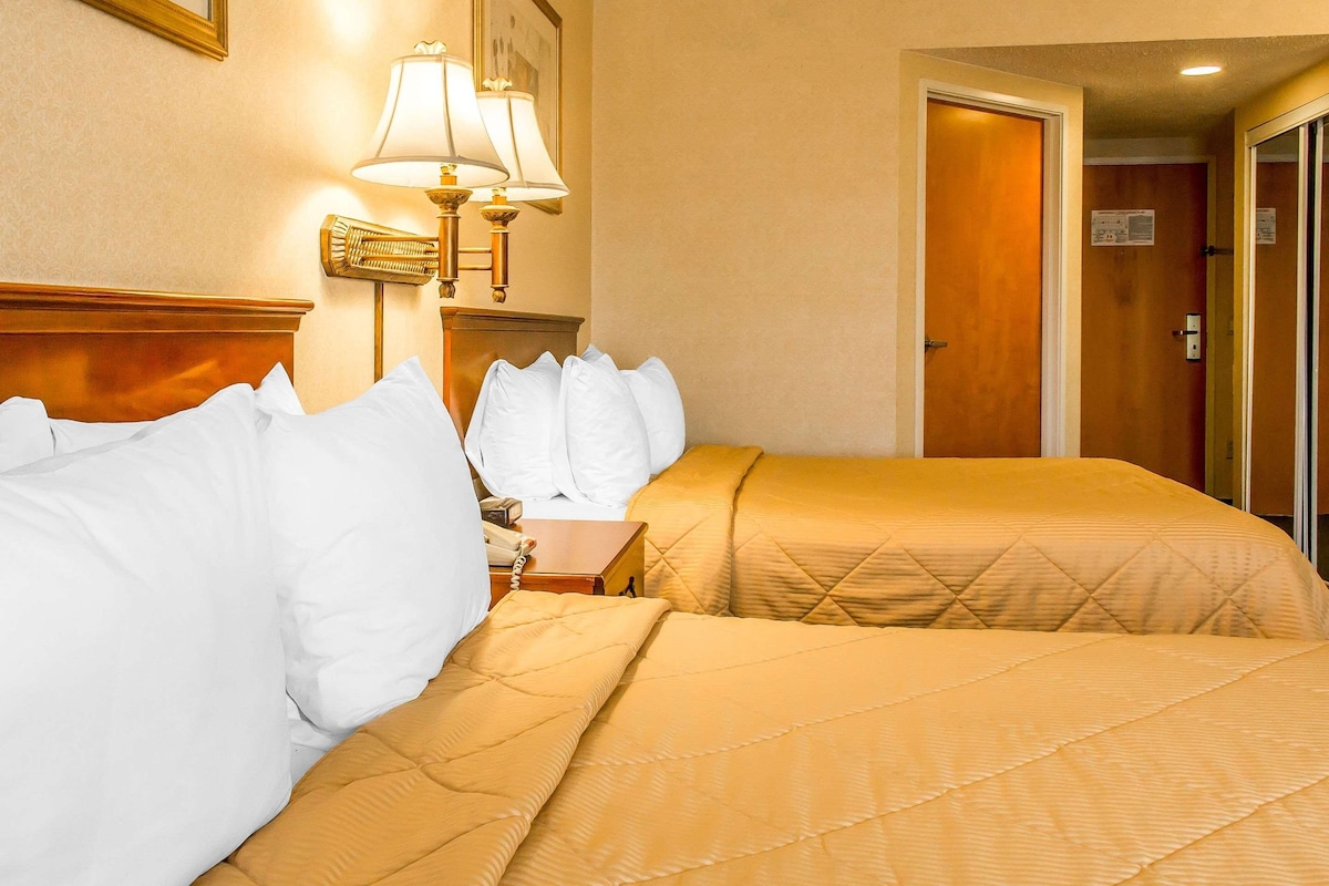 Una habitación de hotel con dos camas, una mesita de noche, una lámpara y una puerta.