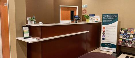 A reception desk with a digital kiosk, a 'No Pets Allowed' sign, and a promotional stand for Choice Privileges.
