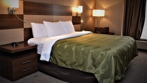 A hotel room with a bed, nightstands, and wall-mounted lamps.