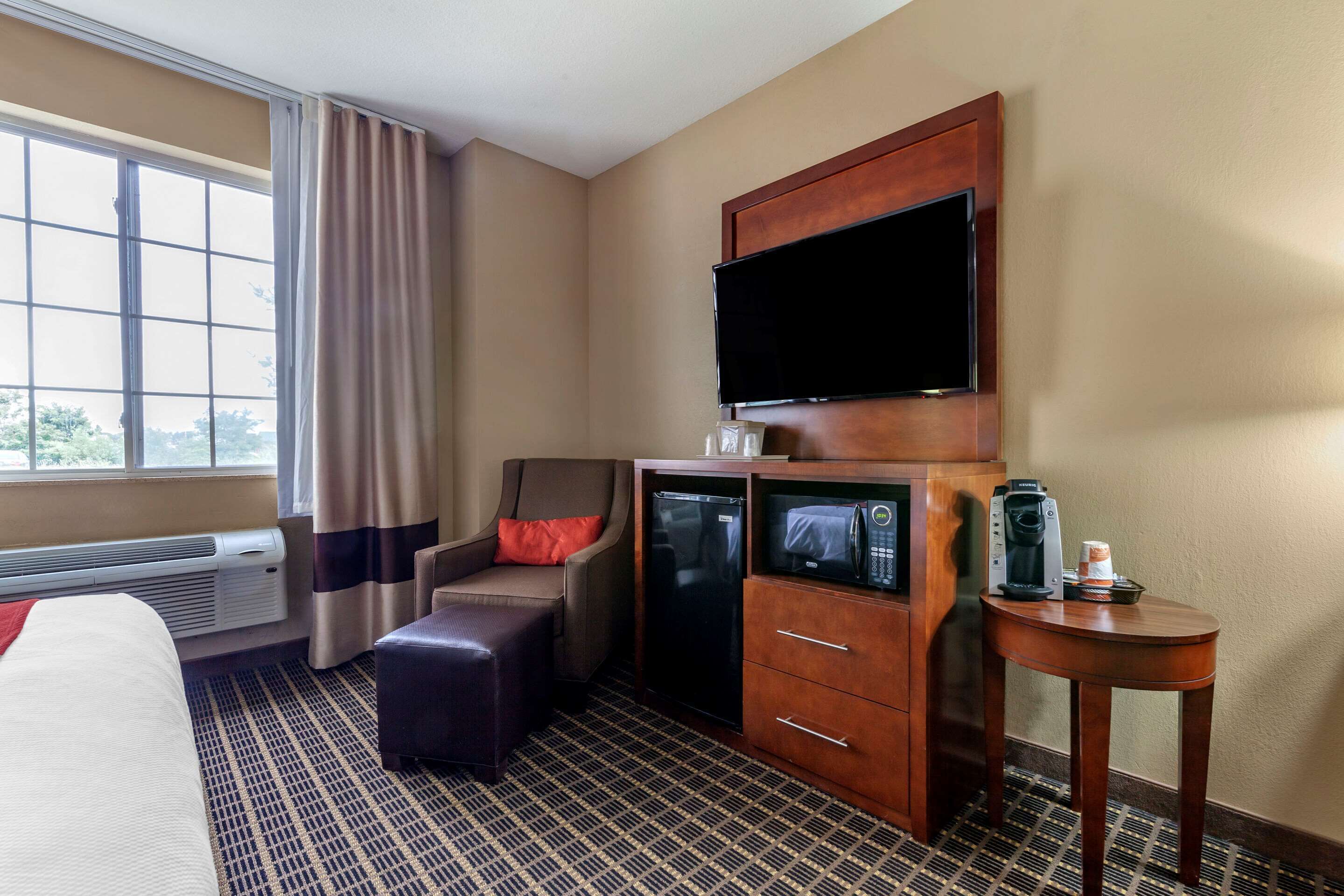 Une chambre d’hôtel équipée d’un lit, d’un bureau avec une machine à café, d’un four à micro-ondes et d’un téléviseur fixé au mur.