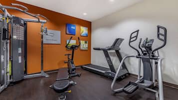 Ett gym med konditionsmaskiner, en viktbänk och en TV som är monterad på väggen.