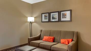 Um hall de hotel com um sofá, duas fotos emolduradas e um abajur.