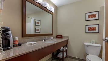 Un baño de hotel con lavamanos doble, un espejo grande, una cafetera y un inodoro.