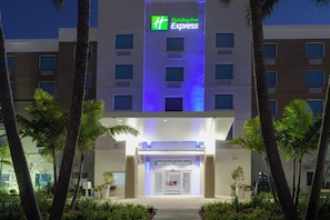 Un hotel Holiday Inn Express con una fachada moderna, varios pisos y una entrada bien iluminada.