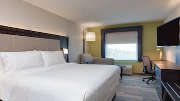 Une chambre d’hôtel avec un grand lit, un bureau, une chaise, une télévision et une fenêtre donnant sur un beau paysage.