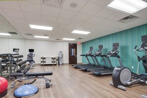 Un gimnasio con cintas de correr, elípticas y pesas libres.