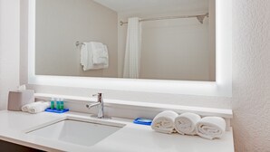 Un baño con un espejo grande, un lavabo y un perchero para toallas.