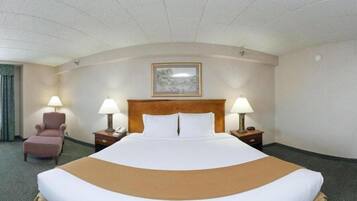A hotel room with a large bed, two bedside tables with lamps, a chair, and a painting on the wall.