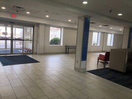 A spacious lobby with a clear exit sign, a reception desk, and a seating area.