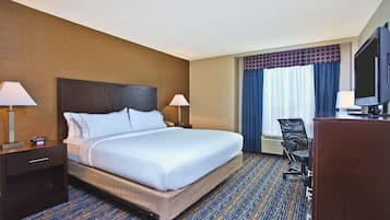 Habitación de hotel con una cama grande, dos mesitas de noche con lámparas, un escritorio con una silla y un televisor.