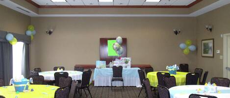 A conference room with multiple tables, chairs, and a projector screen.