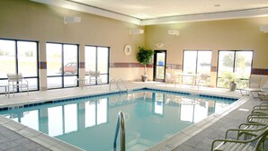 An indoor swimming pool with clear glass walls, a tiled floor, and multiple lounge chairs around the pool area. - Hampton Inn Lebanon (Lebanon)