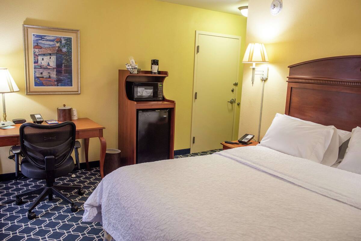 Une chambre d’hôtel équipée d’un lit, d’un bureau, d’une chaise, d’un four à micro-ondes et d’une porte.