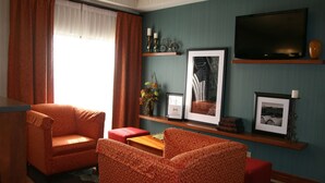 A living room with a sofa, armchair, and a television on a wall. - Hampton Inn Lebanon (Lebanon)