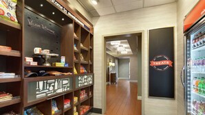 A snack and beverage display area with shelves stocked with various snacks and a refrigerated section with drinks. - Hampton Inn & Suites Montgomery-EastChase (Montgomery)
