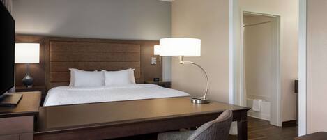 A hotel room with a bed, bedside lamps, a desk, and a chair.