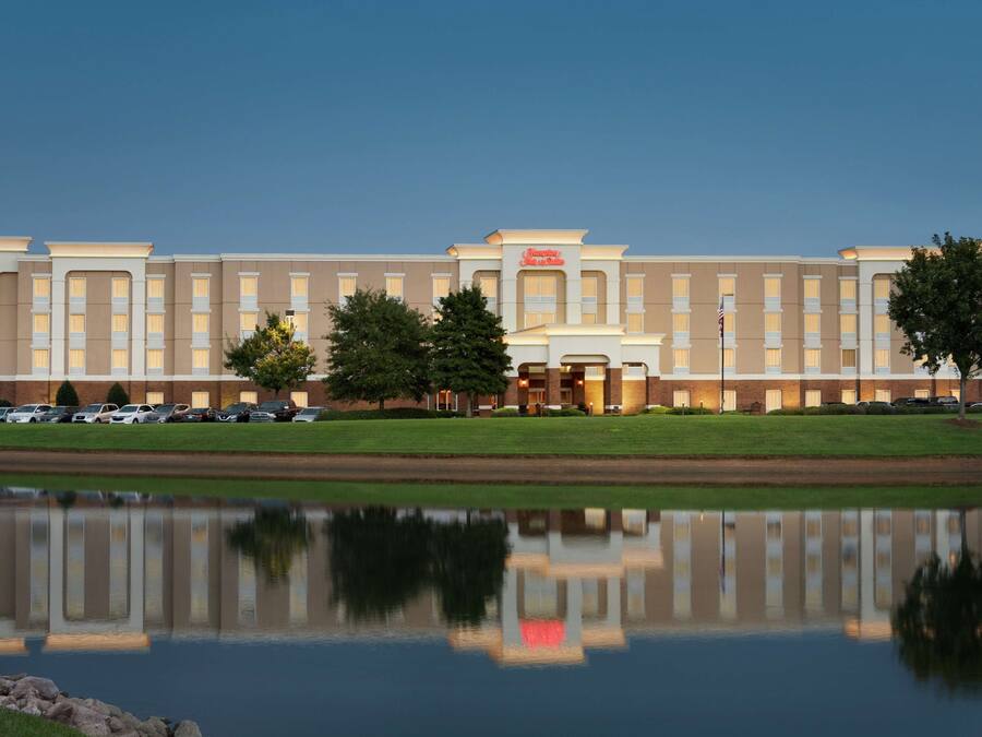 A hotel with a reflection in a body of water, featuring a symmetrical facade, multiple windows, and a central entrance.