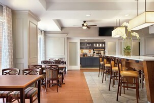 Una cocina moderna con barra, sillas de madera y una mesa de comedor.