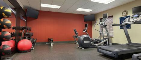 Une salle de sport équipée de tapis de course, d’un vélo d’appartement et de différents ballons d’exercice.