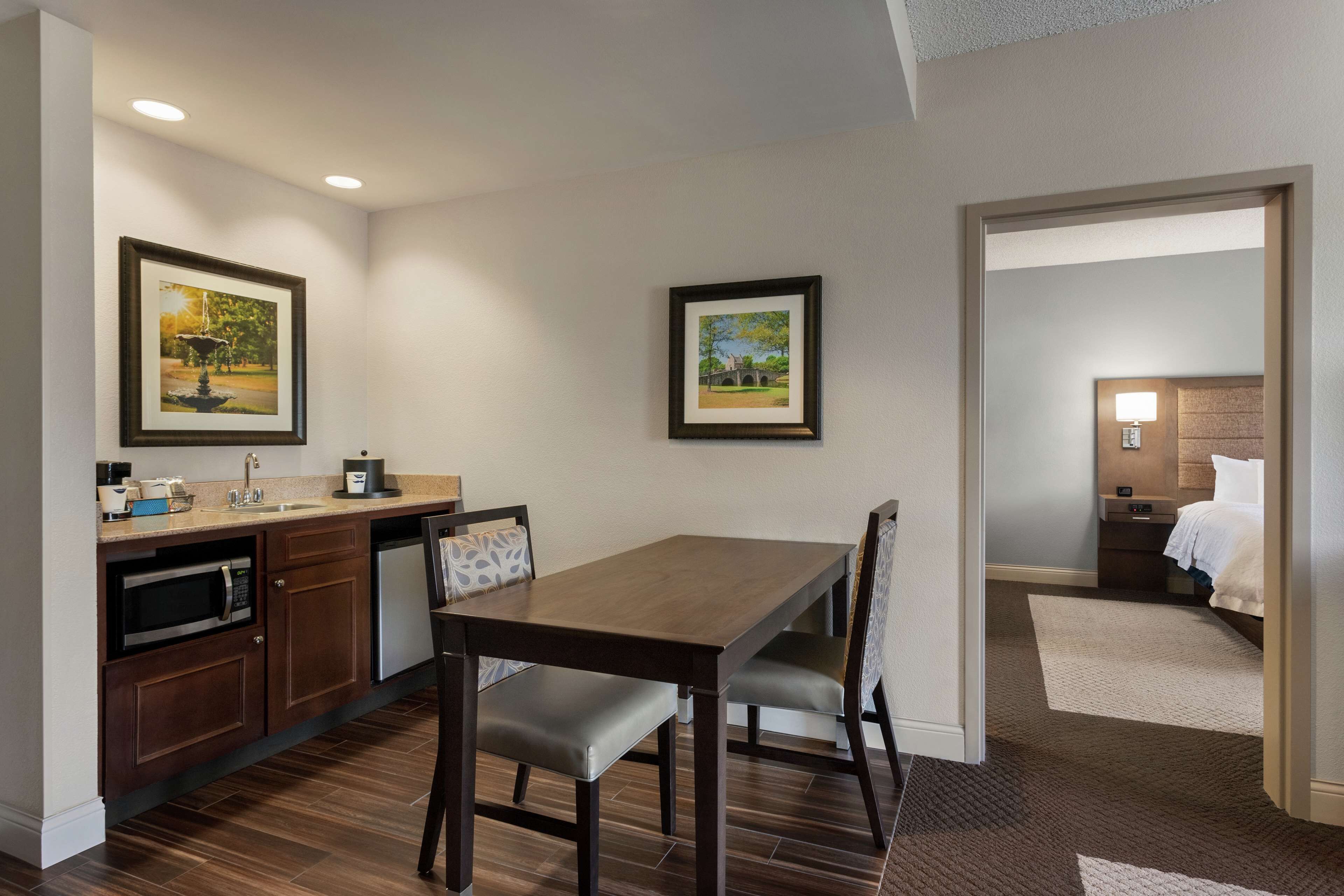 A hotel room with a dining area, kitchenette, and a bed.
