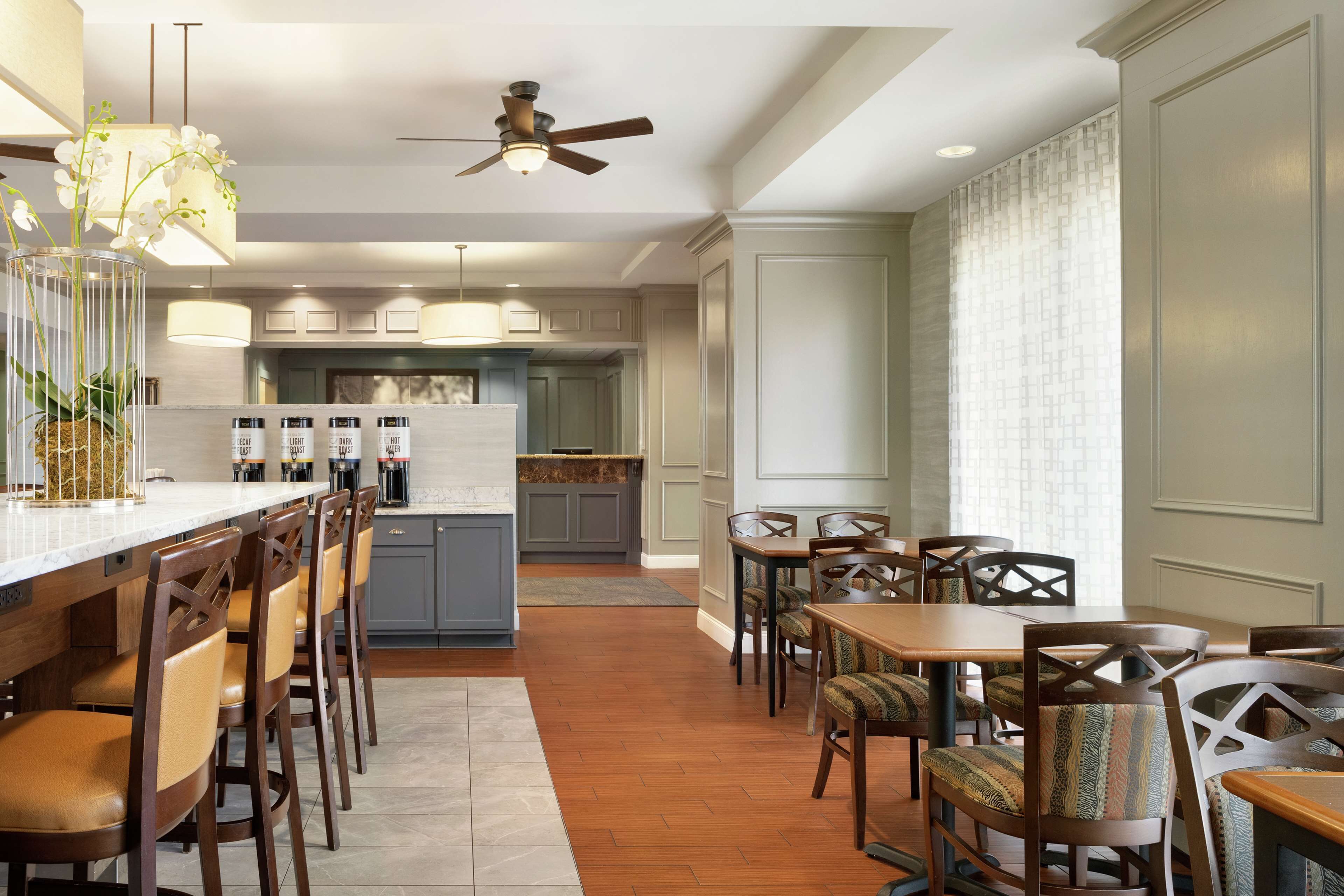 Una cocina moderna con una isla central, sillas de madera y un comedor con mesa y sillas.