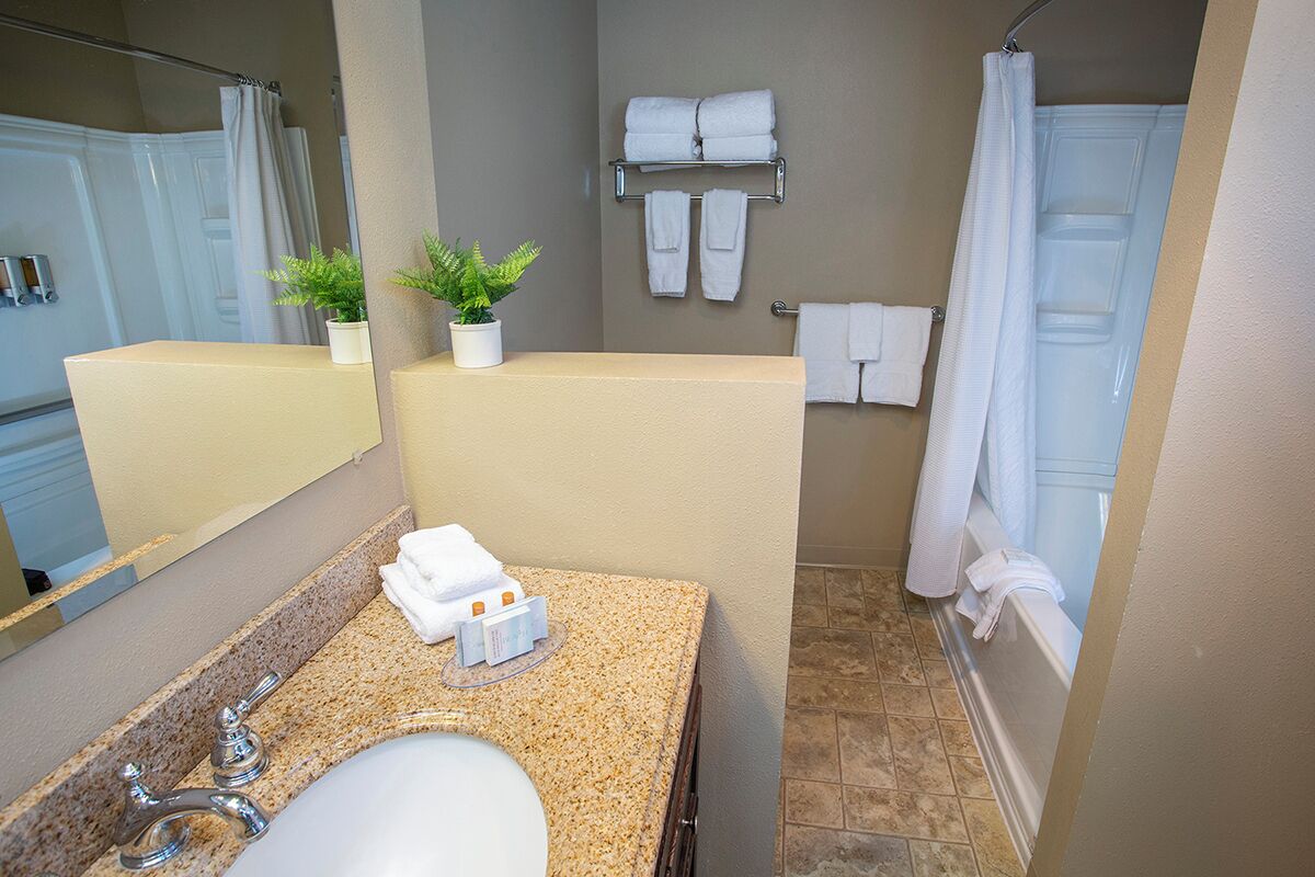 A bathroom with a sink, mirror, towel rack, and shower curtain.