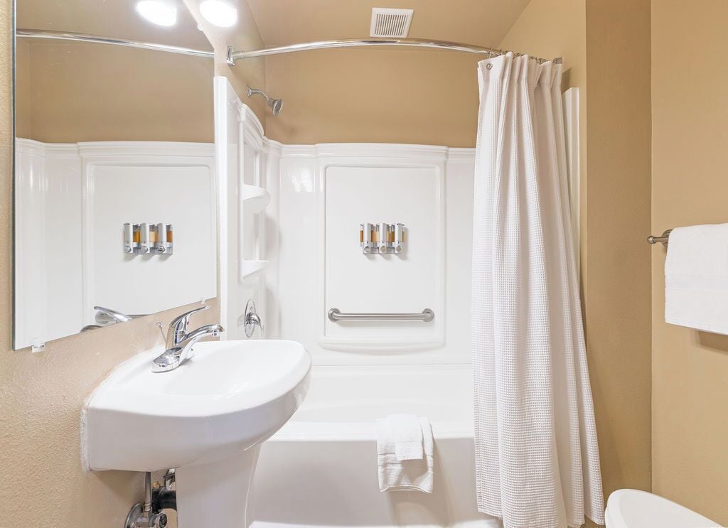 A bathroom with a sink, mirror, bathtub, and shower curtain.