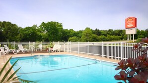 A pool area with white lounge chairs and a sign for Whispering Hills Inn. - Whispering Hills Inn (Branson)