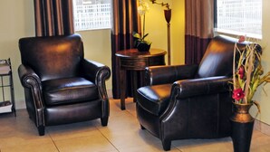 A room with two leather armchairs, a small round table with a lamp, and a vase with flowers. - Whispering Hills Inn (Branson)