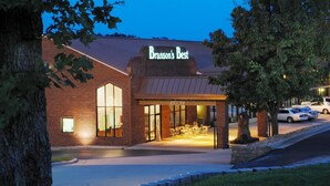 Un edificio de ladrillo con un letrero que dice "Branson's Best" y una entrada cubierta con mesas y sillas.