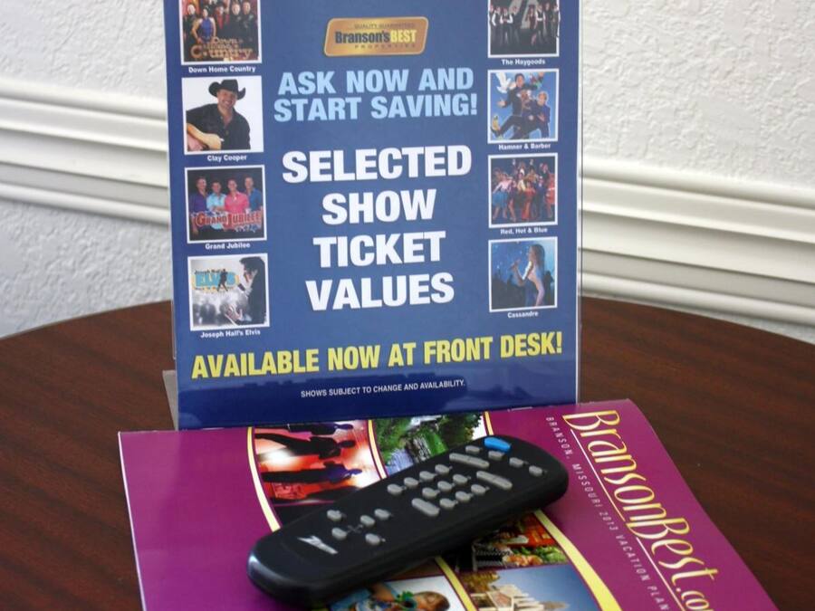 A display stand with show tickets and a remote control on a table.