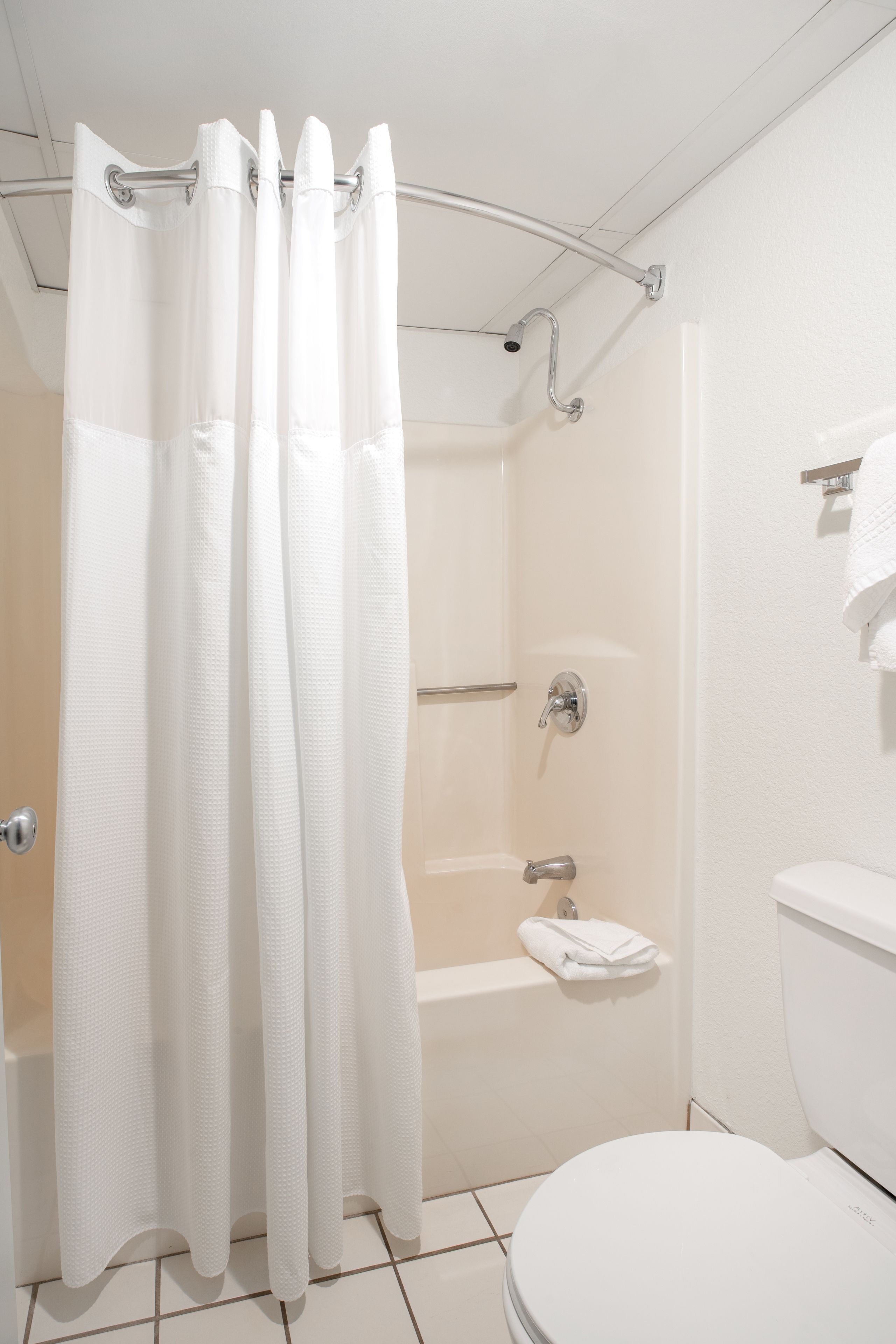 A bathroom with a shower, toilet, and a towel rack.