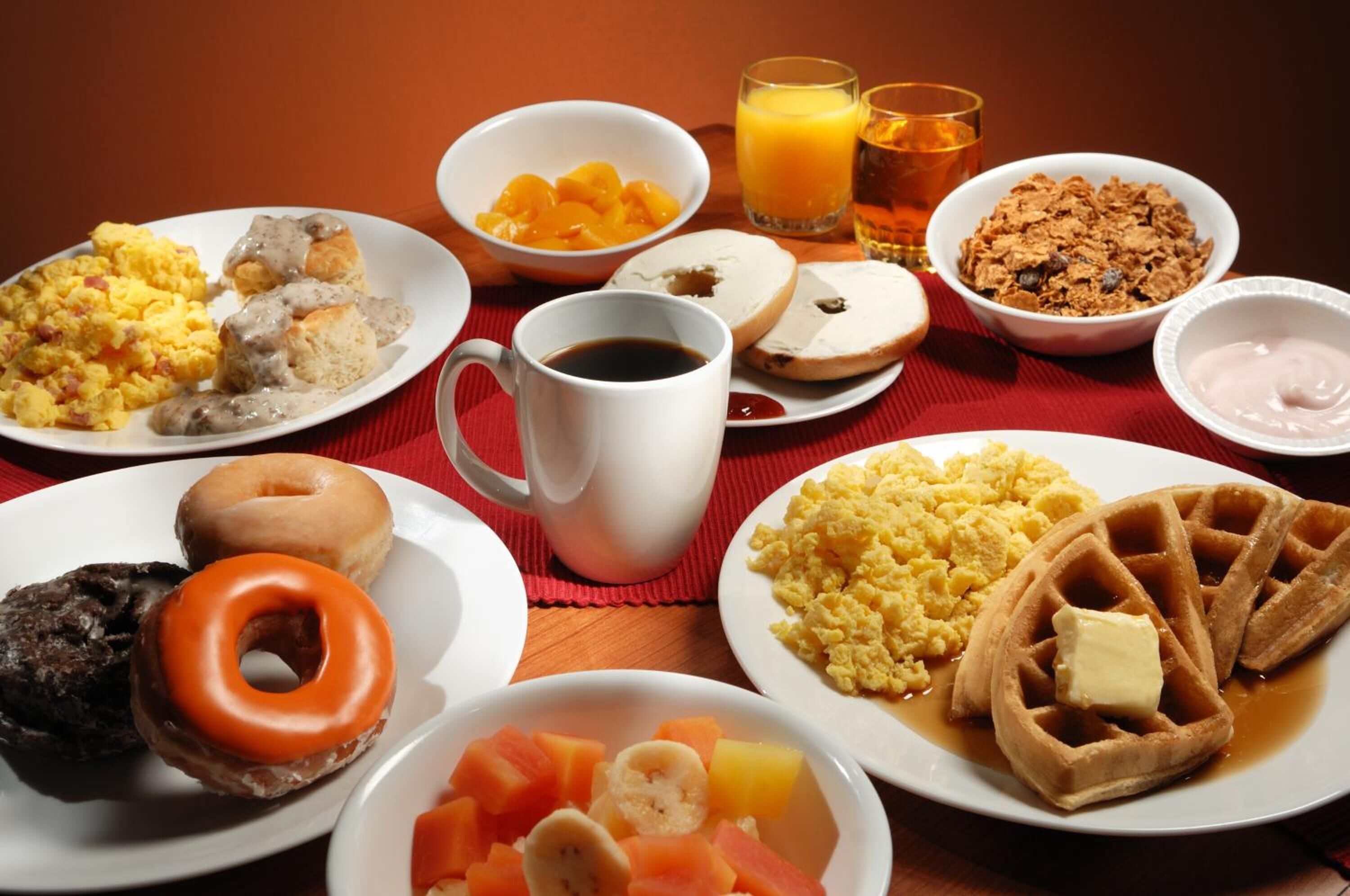 A breakfast table with various dishes including scrambled eggs, waffles, and pastries.