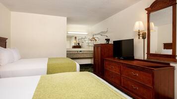 Una habitación de hotel con dos camas, un aparador, un televisor y un espejo.
