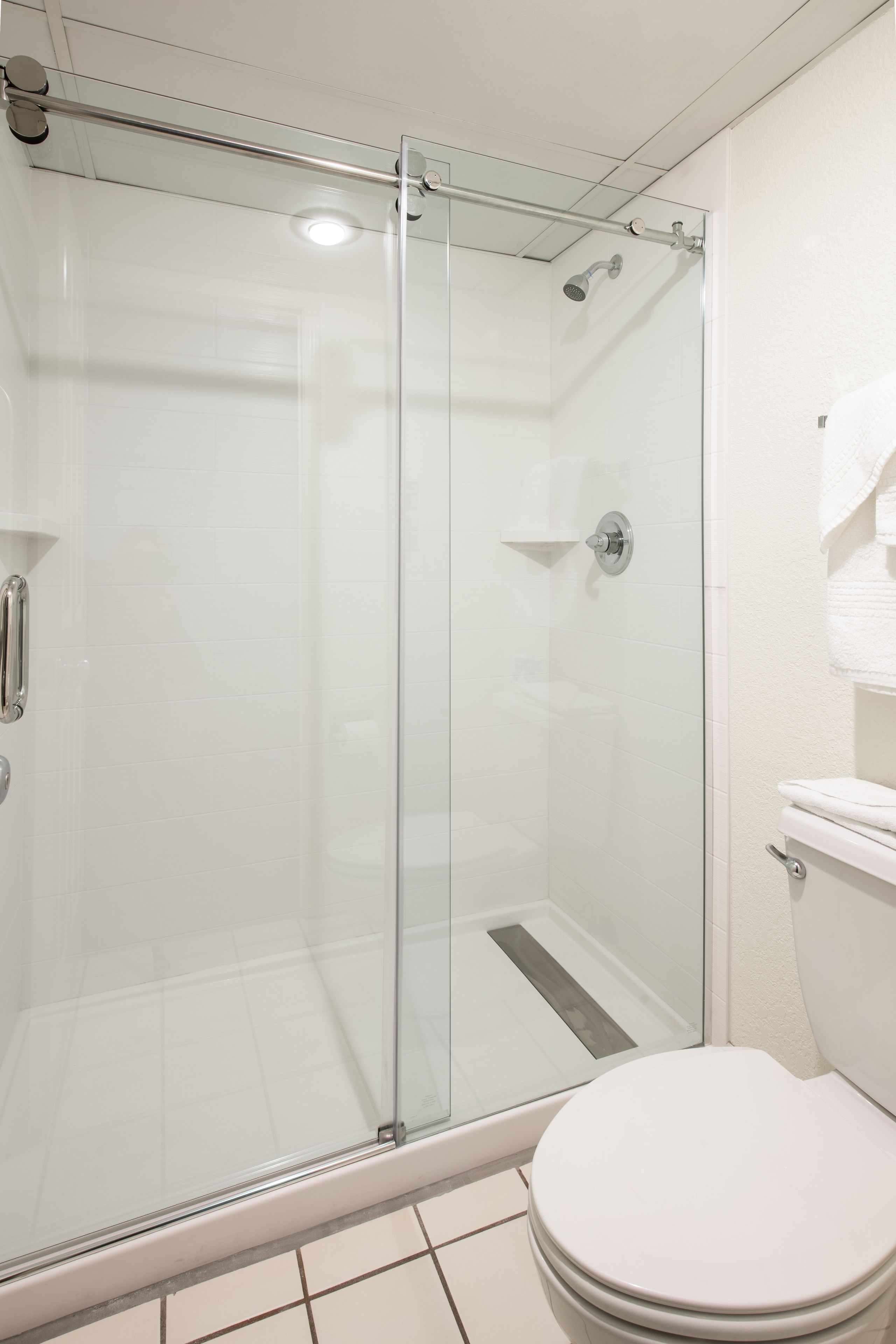 A bathroom with a glass-enclosed shower, a white toilet, and a tiled floor.