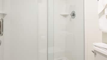 A bathroom with a glass-enclosed shower, a white toilet, and a tiled floor.