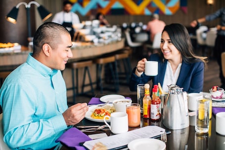 A breakfast setting with a table set for two, including plates of food, drinks, and condiments.