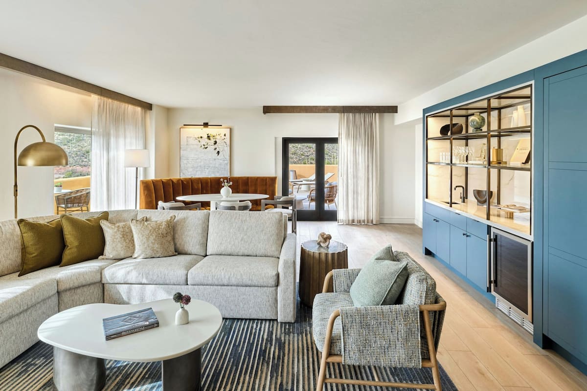 A modern living room with a sectional sofa, a round coffee table, and a dining area with a view.