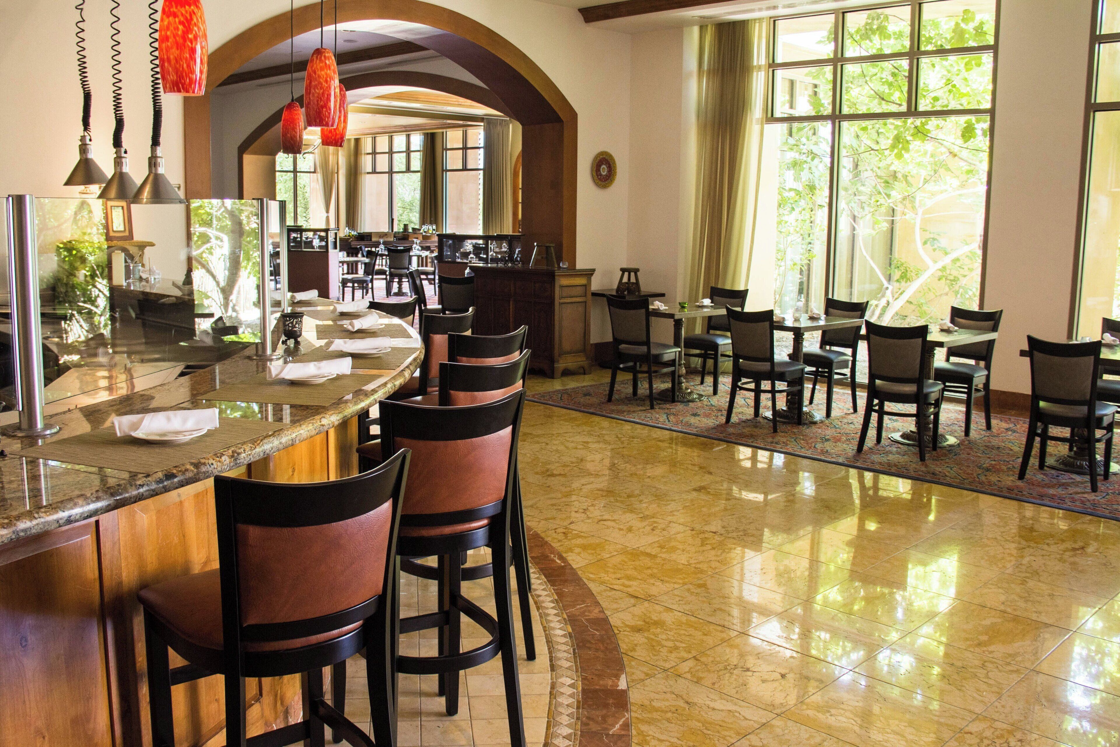 A restaurant with a bar area, multiple tables, and chairs.