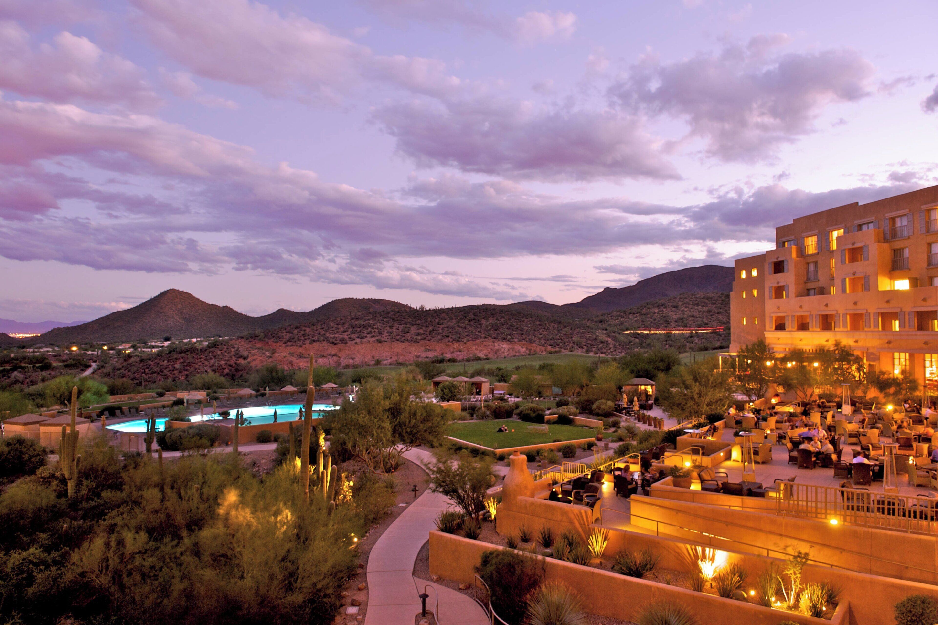 A hotel with outdoor seating, a pool, and a desert landscape in the background.