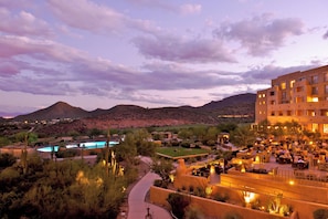 A hotel with outdoor seating, a pool, and a desert landscape in the background. - JW Marriott Starr Pass Resort and Spa (Tucson)