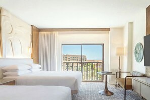 Une chambre d’hôtel avec deux lits, un balcon, une petite table et un téléviseur.