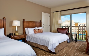 A hotel room with two beds, a wooden headboard, a nightstand with a lamp, a chair, and a balcony with a view of buildings. - JW Marriott Starr Pass Resort and Spa (Tucson)