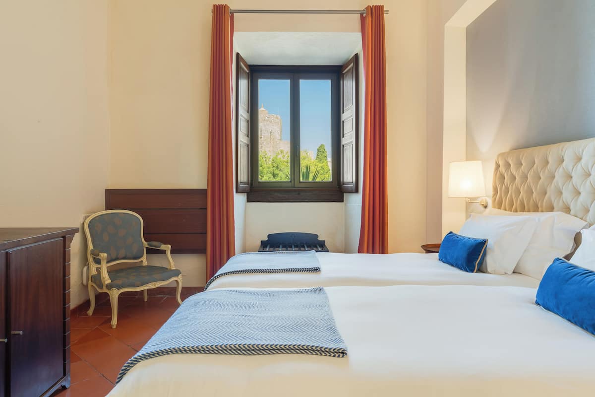 Habitación de hotel con una cama grande, una silla, un escritorio y una ventana con cortinas.