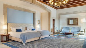 A bedroom with a large bed, a sofa, a chandelier, and a patterned rug. - Pousada Castelo de Palmela - Historic Hotel (Palmela)