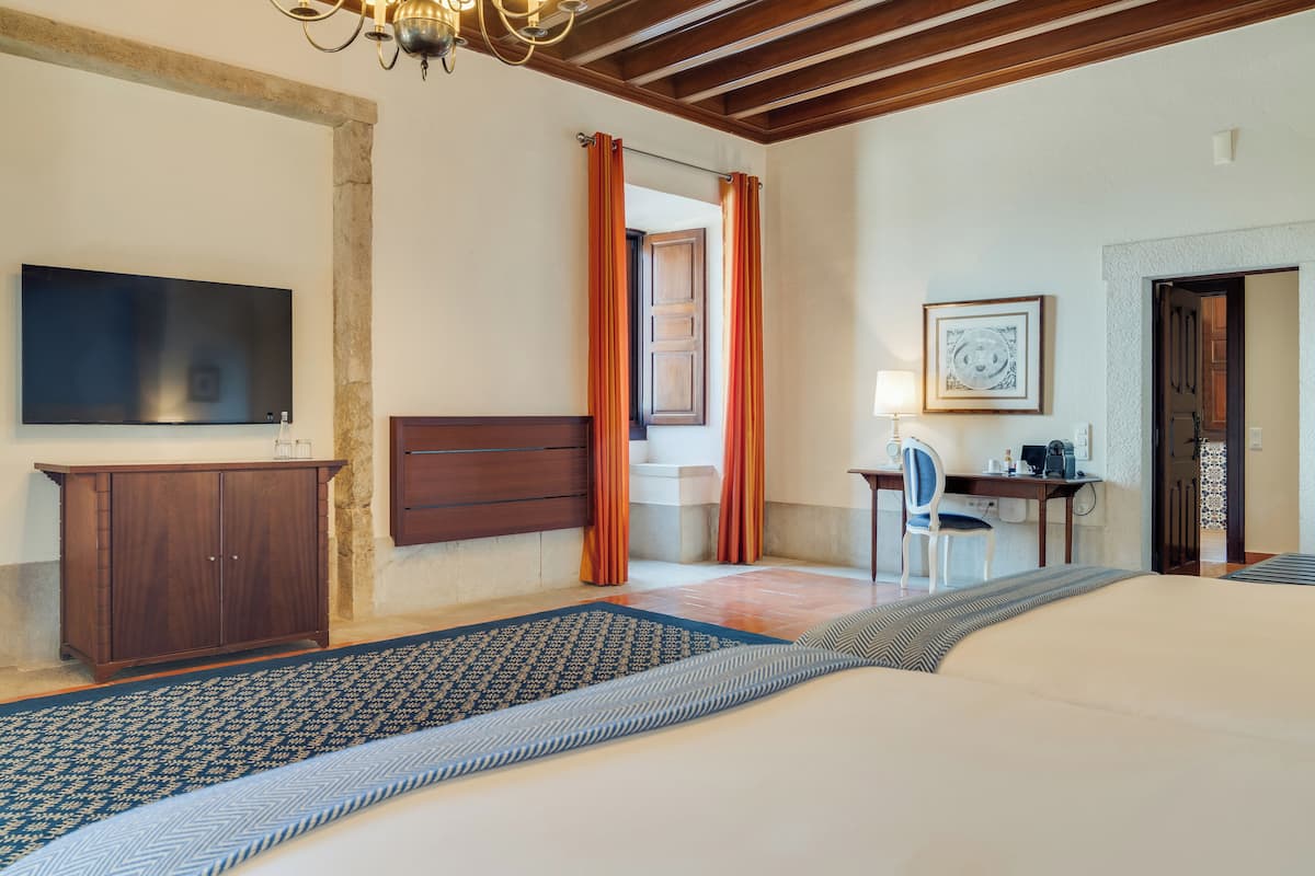 Una habitación de hotel con una cama, un escritorio, una silla, un televisor y una puerta.