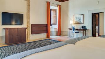 A hotel room with a bed, a desk, a chair, a television, and a door.